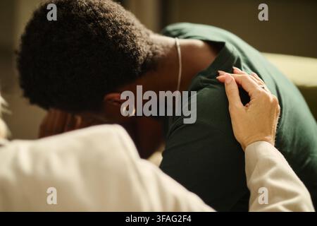 Kaukasische Therapeutin tröstet weinende junge afroamerikanische Frau während einer Therapiesitzung. Bild stellt psychologische Unterstützung dar, geeignet für Beratungsdienste Stockfoto