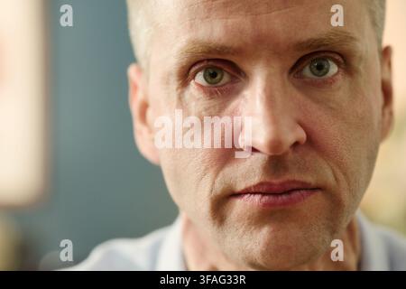 Porträt eines mittelalten kaukasischen Mannes, der mit ernstem Ausdruck direkt in die Kamera blickt. Nahaufnahme, ideal für Kampagnen zum Bewusstsein für psychische Gesundheit oder redaktionelle Gesundheitsinhalte Stockfoto