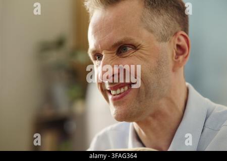 Mittealter Mann kaukasischer Abstammung lächelt während eines Gesprächs und zeigt positive Emotionen. Nahaufnahme, ideal für Kampagnen zum mentalen Wohlbefinden, Zahnpflege-Marketing oder Gesundheitsdienstleistungen Stockfoto