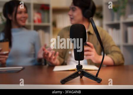 Mikrofon-Nahaufnahme mit asiatischem Mann und Frau, die eine Podcast-Episode im Heimstudio aufnehmen Stockfoto