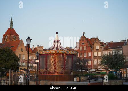 Niedrigwinklige Ansicht historischer gemusterter Fassaden und eines Vintage-Karussells vor einem klaren Abendhimmel. Stockfoto