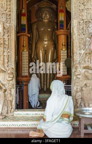 Indien. Bundesstaat Madhya Pradesh. Khajuraho. Gläubige in weißer Ritualkleidung beten vor der monumentalen Statue eines Tirthankara im Shant-Tempel Stockfoto