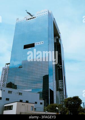 Moderner Glas-Wolkenkratzer mit markanter Lücke in der Fassade vor blauem Himmel in Osaka, Japan Stockfoto