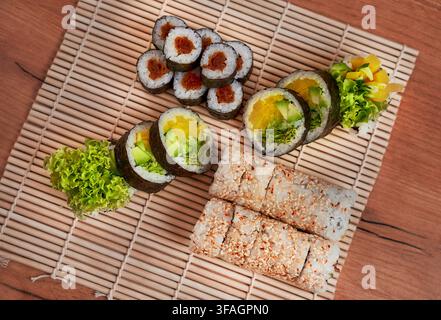 Sortiment an frischen vegetarischen Sushi-Rollen, serviert auf einer traditionellen Bambus-Sushi-Matte. Stockfoto