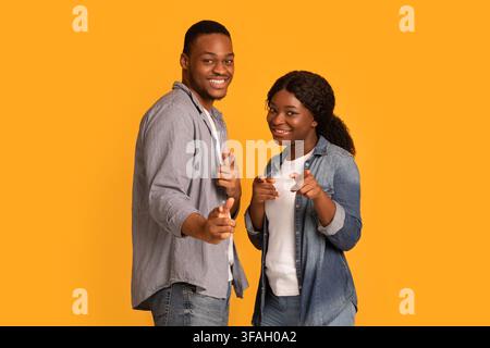 Positives Afroamerikanisches Paar, Das Mit Zwei Händen Auf Camera Zeigt Stockfoto