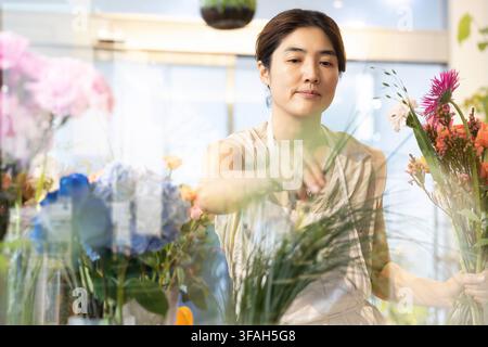 Koreanische Floristin arrangiert einen farbenfrohen Strauß in ihrem Blumenladen Stockfoto