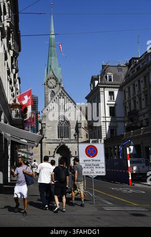 Die St. Peters Kirche in Zürich, Schweiz, erscheint im Hintergrund dieser Straßenansicht, erkennbar an ihrem markanten grünen Turm und der großen Uhr Stockfoto
