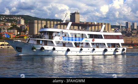 Passagier-Kreuzfahrtschiff Vita segelt in blauen Gewässern des Hafens vor der Stadt Skyline und den Hügeln in Rijeka, Kvarner-Bucht, Kroatien. Stockfoto