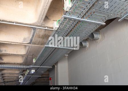 Metallkabelkanäle und Lüftungsrohre sind unter einer Betondecke in einem modernen Industrie- oder Gewerbebauprojekt installiert Stockfoto