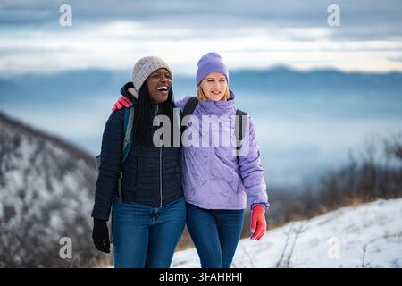 Verschiedene Freundinnen genießen Winterwandern in schneebedeckten Bergen Stockfoto