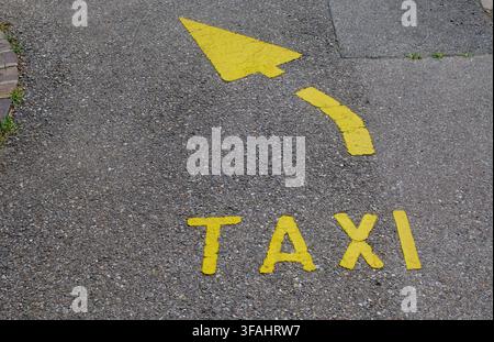 Hochwinkelansicht des Wortes TAXI und eines gebogenen Richtpfeils in Gelb auf Asphalt in Lugano, Schweiz. Konzept für den städtischen Verkehr Stockfoto