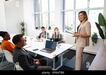 Geschäftsfrau leitet Meeting und präsentiert einem vielfältigen Geschäftsteam Stockfoto
