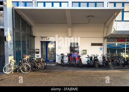 Fahrräder, die an einer weißen Wand unter einem blau umrandeten Vordach im trendigen Meatpacking District (Kødbyen) von Kopenhagen, Dänemark, abgestellt sind. Stockfoto