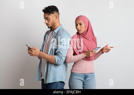 Betrug und Untreue Konzept. Neugierige islamische Frau, die in das Mobiltelefon des Mannes guckt Stockfoto