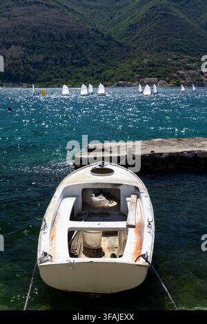 Kleines weißes festgemachtes Fischerboot in einer Meeresbucht mit Segelbooten im Hintergrund Stockfoto