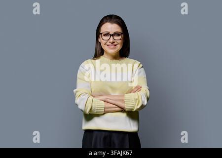 Selbstbewusste lächelnde reife Frau mit Brille und verschränkten Armen, Studio-Porträt Stockfoto