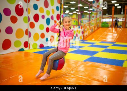 Fröhliches Mädchen fährt auf einer dynamischen Indoor-Schleuder-Schaukel Stockfoto