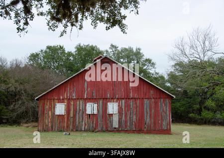 Eine alte rote Scheune im Texas Hill Country hat bessere Tage gesehen. Ihre abblätternde Farbe verleiht ihr ein sehr rustikales Aussehen. Stockfoto