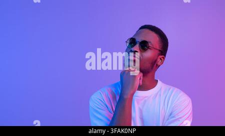 Porträt Des Nachdenklichen Afroamerikanischen Guy In Stilvollen Brillen In Neonlicht Stockfoto