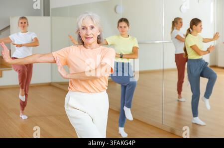 Positive Frau macht Aerobic-Übungen mit einer Gruppe von Menschen im Tanzzentrum Stockfoto