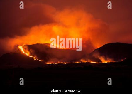 Nachtansicht eines Waldbrandes, der an den Hängen brennt, mit Flammen und Rauch, die den dunklen Himmel erhellen. In Sierra de la Ventana, Provinz Buenos Aires Stockfoto