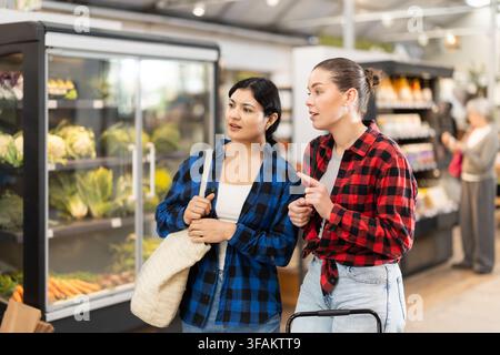 Zwei junge Frauen reden und wählen Essen im Supermarkt aus Stockfoto