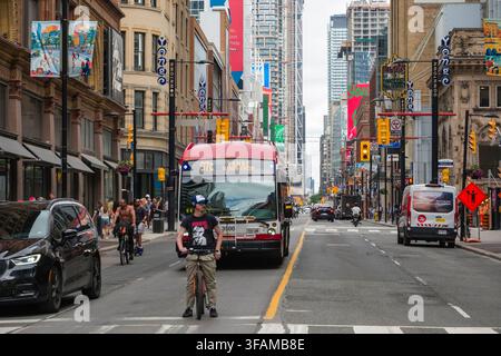 Erleben Sie die lebendige Energie der Innenstadt von Toronto, Ontario, Kanada. Diese geschäftige Straßenszene zeigt einen typischen Tag mit öffentlichen Verkehrsmitteln, Fahrzeugen Stockfoto