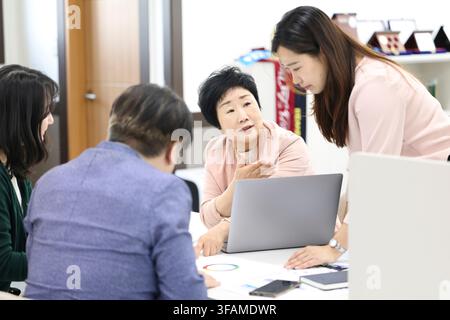 Senior-Koreanische-Frauenmanagerin leitet eine Teambesprechung in einem modernen Büro Stockfoto