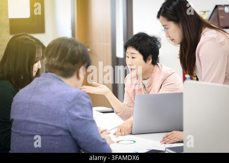 Senior-Koreanische-Frauenmanagerin leitet eine Teambesprechung in einem modernen Büro Stockfoto