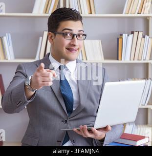 Der Geschäftsmann mit einem Laptop arbeitet in der Bibliothek Stockfoto