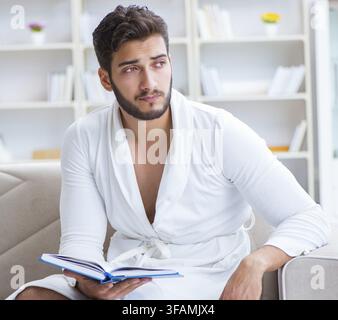Junger Mann, Student, Geschäftsmann liest ein Buch, lernt und arbeitet zu Hause Stockfoto