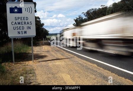 EIN LKW PASSIERT EINEN STRASSENRAND-Geschwindigkeitskontroll-Warntafel auf einer Landstraße in New South Wales, Australien. Stockfoto