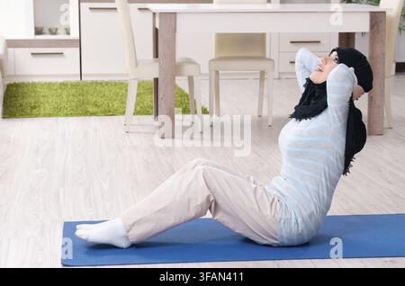 Die junge Frau mit dem Hijab macht zu Hause Übungen Stockfoto