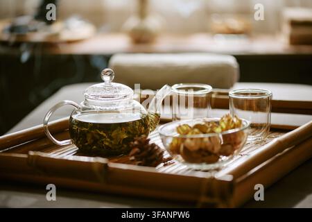 Kräutertee in gläserner Teekanne auf Bambustablett im Spa-Salon Stockfoto