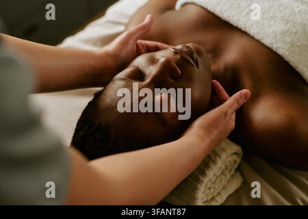 Schwarze Frau erhält entspannende Gesichtsmasage in einem Wellness-Spa Stockfoto