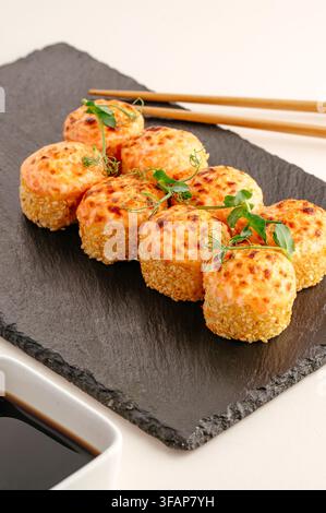 Gebackene Sushi-Rollen mit Sesam auf einer Schieferplatte Stockfoto
