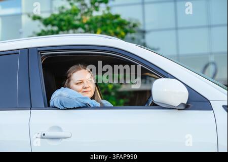 Frau schaut nachdenklich aus dem Autofenster Stockfoto