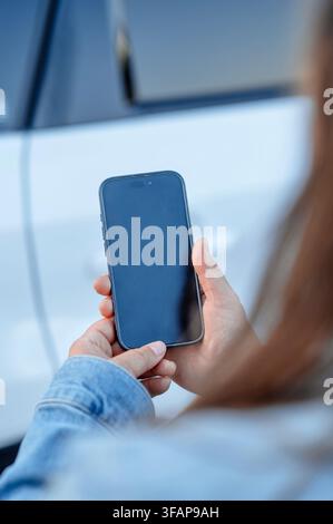 Frau in Jeansjacke hält ein Smartphone Stockfoto