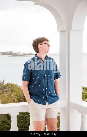 Junger Mann mit Brille genießt den Meerblick vom Balkon Stockfoto
