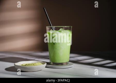 Eis-Matcha-Latte mit Papierstrohhalm auf einer Marmorarbeitsplatte Stockfoto