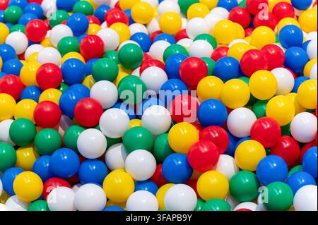 Viele helle Plastikkugeln bilden einen verspielten und farbenfrohen Vollrahmen-Hintergrund Stockfoto