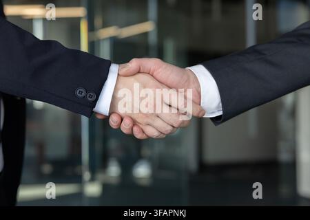 Zwei Geschäftsleute, die sich bei einer Nahaufnahme die Hände schütteln, symbolisieren eine erfolgreiche berufliche Partnerschaft, Zusammenarbeit und Übereinkunft nach einem Meeting oder einer Verhandlung Stockfoto