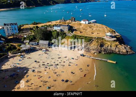 Tenby Castle Hill und North Beach bei Ebbe im Sommer, Badegäste ruhen auf dem Sand unterhalb der Küstenklippe und Tenby Museum, Pembrokeshire, Wales Stockfoto