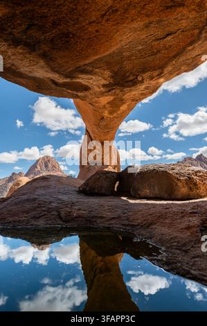 Natürlicher Felsbogen mit Reflexionsbecken und Spitzkoppe-Gipfeln im Hintergrund, Namibia Stockfoto