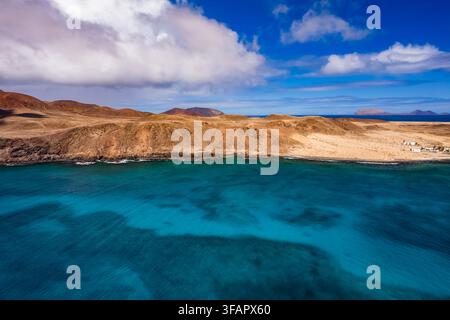 Aus der Vogelperspektive sehen Sie die felsige Landschaft von Lanzarote und den Kanarischen Inseln La Graciosa. Klares türkisfarbenes Wasser trifft unter A auf die Küste Stockfoto
