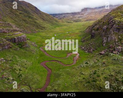 Luftbilddrohnenaufnahme des Flusses Aguas Tuertas, der sich durch ein grünes Tal in den Valles Occidentales in den Pyrenäen schlängelt Stockfoto