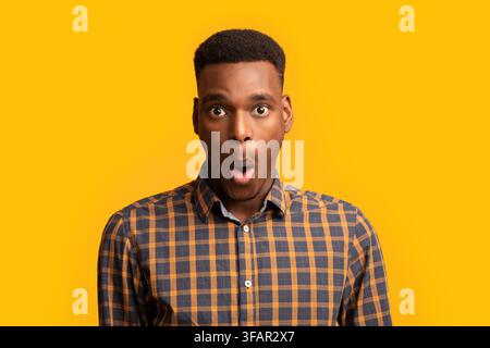 Porträt Von Überrascht African American Guy Geöffnet Mund In Erstaunen, Gelber Hintergrund Stockfoto