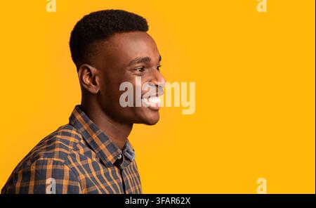Seitenansicht eines fröhlichen Millennial afrikaners, isoliert auf gelbem Hintergrund. Stockfoto