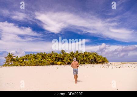 Mann geht am Strand von Honeymoon Island in Aitutaki, Cookinseln, in der Nähe des Lagunen an einem sonnigen Tag entlang Stockfoto