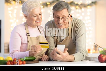 Ältere Ehepaare Nutzen Handy- Und Kreditkarteneinkäufe Im Haus Stockfoto